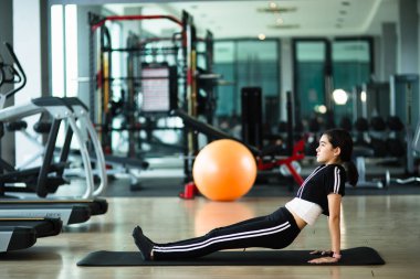 Genç ve güzel bir kız ısınıyor ve spor salonunda şınav çekiyor.