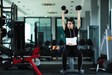 Spor salonunda halterle egzersiz yapan güzel bir kız..