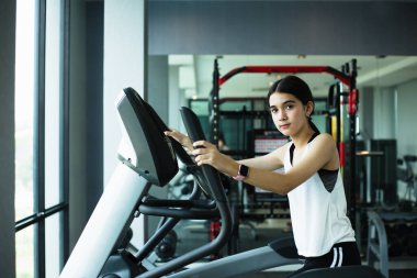Spor salonunda Eliptik Egzersiz yapan Asyalı kız spor yapıyor. Zayıf ve sağlıklı yaşam tarzı için makine aerobiğiyle kilo veriyor.