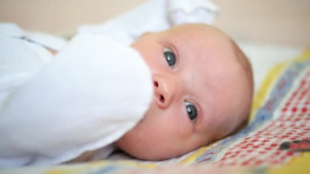 Portret Een Close Baby Witte Kleren Ligt Zijn Rug Zwaait — Stockvideo