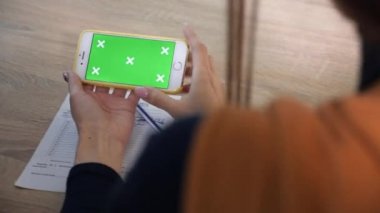 İki kız akıllı telefondan el kol hareketi videosu izliyor. Yeşil ekran. Kamera sola kaydıraçla hareket ediyor..