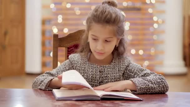 若い女の子が本のページを通して葉や新年のための贈り物の夢 背景には 新年の光が輝きます — ストック動画
