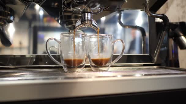Starkt espressokaffe kommer från kaffemaskiner och går i två glas koppar — Stockvideo