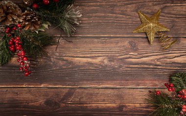 Noel ağacı, böğürtlenli çam kozalakları ve karlı altın bir noel ağacının yanında ahşap arka planda.