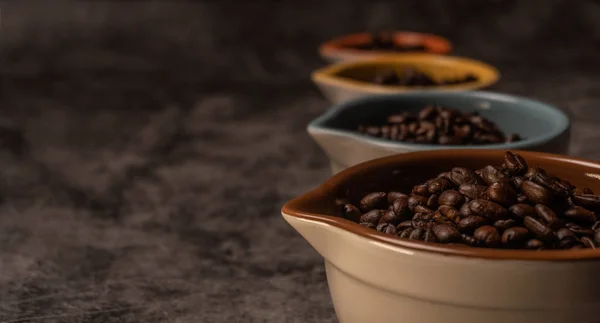 Vista lateral de granos de café orgánicos frescos dentro de muchas tazas de cerámica de colores — Foto de Stock
