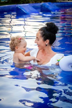 Anne ve küçük bebek havuzda yüzerken iyi eğlenceler.