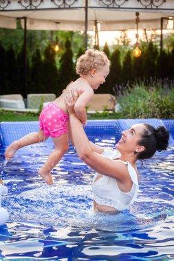 Anne ve küçük bebek havuzda yüzerken iyi eğlenceler.