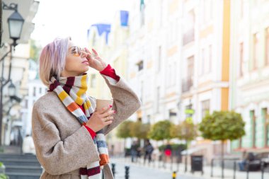 Genç bir kadın eski şehirde bir fincan kahveyle yürüyor. Yaşam biçimi.