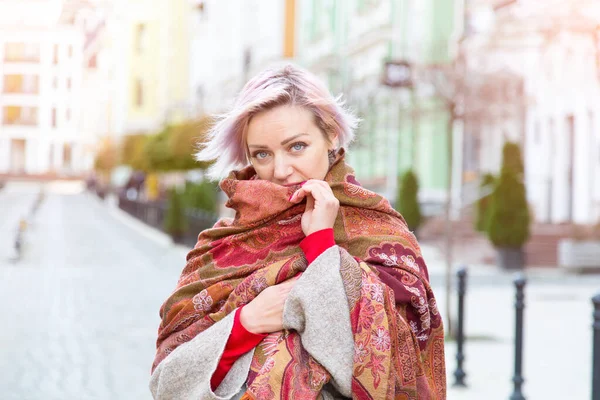 Portrait of a young woman in a scarf on the background of the city.