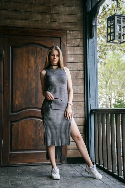 Model in grey dress in front of wooden building — Stock Photo, Image