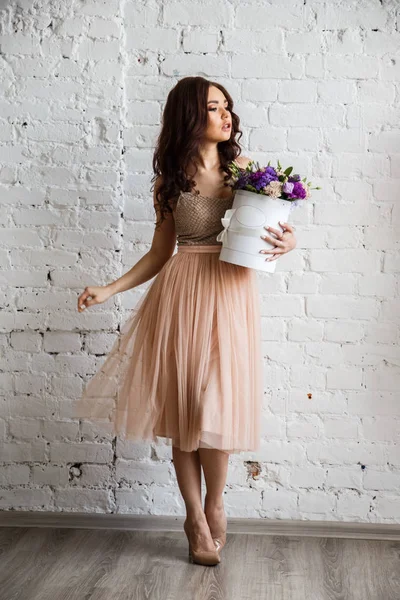 Junge Brünette im schönen Kleid mit Blumen — Stockfoto