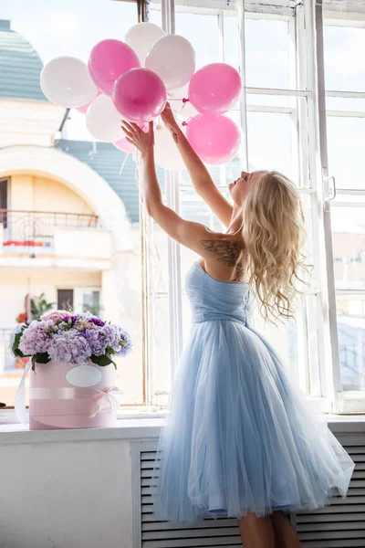 Meisje in een blauwe jurk bedrijf lucht ballonnen — Stockfoto