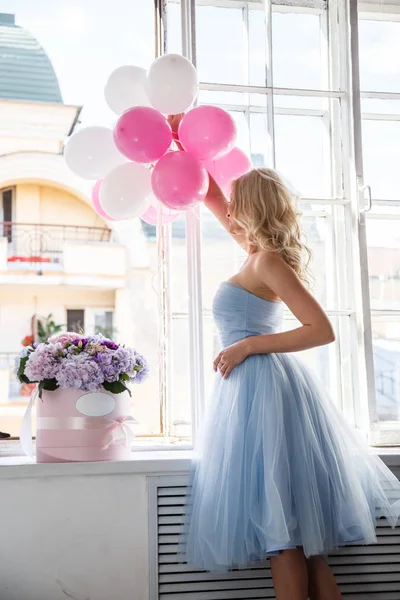 Meisje in een blauwe jurk bedrijf lucht ballonnen — Stockfoto