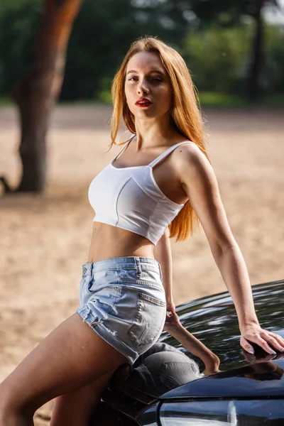 Blonde in top and shorts near the car — Stock Photo, Image