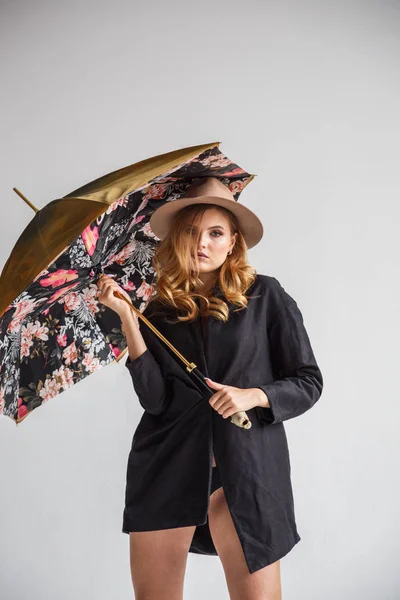 model in black shirt and hat with umbrella