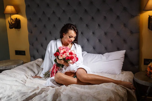 메이크업 가운의 스튜디오 초상화 꽃다발 배경으로 침대에 — 스톡 사진