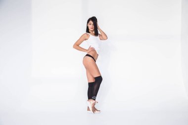 Güzel esmer kız siyah iç çamaşırı ve Beyaz tişört stüdyo çekim. Sportif vücut ayakta beyaz stüdyo arka plan üzerinde olan güzellik kadın