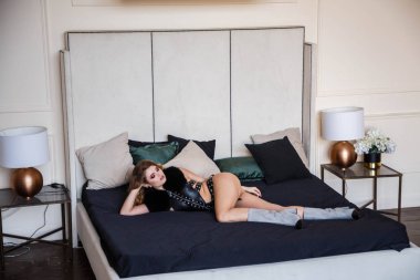 Stüdyo portre güzellik modeli giymiş siyah deri iç çamaşırı. Şık makyaj evde koltukta yalan olan cinsel kadın 