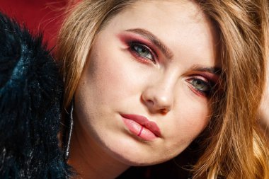 Portre güzellik modeli giymiş mavi ceket. Şık makyaj kırmızı kanepede yatan genç kadın