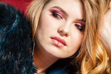 Portre güzellik modeli giymiş mavi ceket. Şık makyaj kırmızı kanepede yatan genç kadın