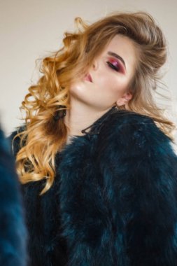 Stüdyo portre güzellik modeli giymiş siyah bluz ve mavi ceket. Aynaya bakarak şık makyaj ile genç kadın 