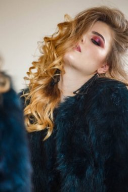 Stüdyo portre güzellik modeli giymiş siyah bluz ve mavi ceket. Aynaya bakarak şık makyaj ile genç kadın 