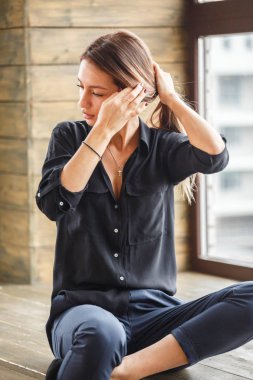 Ahşap zemin, ışıklı windows arka plan üzerinde oturan siyah rahat kıyafetler giymiş güzel genç kadın stüdyo çekim