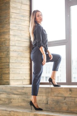 Stüdyo çekim ayakta siyah casual elbiseler giymiş güzel genç kadının iç ışıklı windows arka plan ile Anasayfa