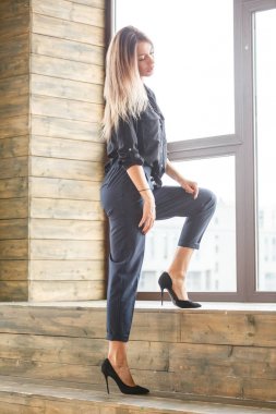 Stüdyo çekim ayakta siyah casual elbiseler giymiş güzel genç kadının iç ışıklı windows arka plan ile Anasayfa