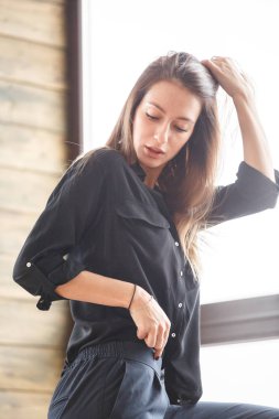 Stüdyo çekim ayakta siyah casual elbiseler giymiş güzel genç kadının iç ışıklı windows arka plan ile Anasayfa