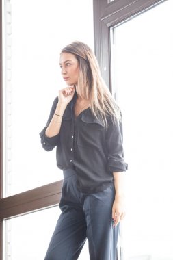 Stüdyo çekim ayakta siyah casual elbiseler giymiş güzel genç kadının iç ışıklı windows arka plan ile Anasayfa
