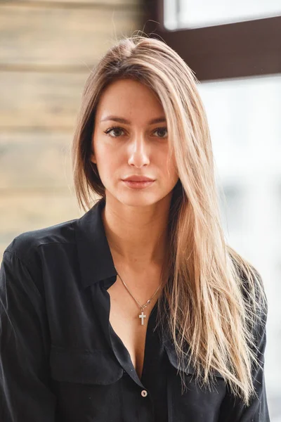 Ahşap zemin, ışıklı windows arka plan üzerinde oturan siyah rahat kıyafetler giymiş güzel genç kadın stüdyo çekim