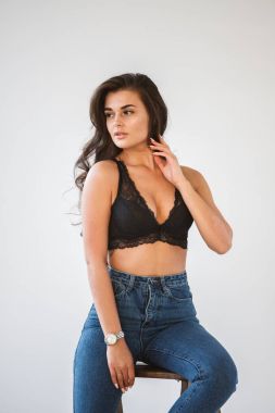 Mavi jeans ve Ahşap merdiven, beyaz duvar arka plan eğilerek cinsel siyah iç çamaşırı giyen güzel kıvırcık esmer kız portresi stüdyo