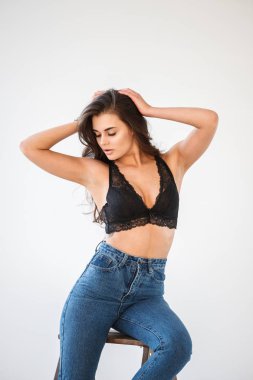 Mavi jeans ve Ahşap merdiven, beyaz duvar arka plan eğilerek cinsel siyah iç çamaşırı giyen güzel kıvırcık esmer kız portresi stüdyo