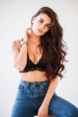 Mavi jeans ve Ahşap merdiven, beyaz duvar arka plan eğilerek cinsel siyah iç çamaşırı giyen güzel kıvırcık esmer kız portresi stüdyo