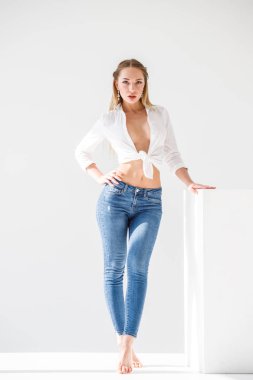 Kot ve beyaz stüdyo arka plan ayakta beyaz gömlek giymiş seksi sarışın kız portresi
