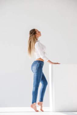Kot ve beyaz stüdyo arka plan ayakta beyaz gömlek giymiş seksi sarışın kız portresi