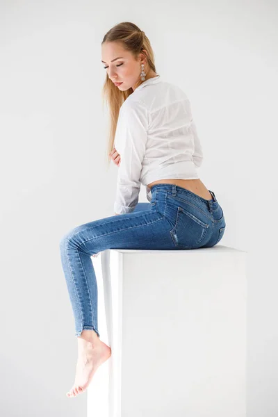 Portret Seksowna Blondynka Sobie Niebieskie Dżinsy Białej Koszuli Siedzi Tle — Zdjęcie stockowe