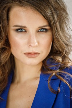 Portre stüdyo portre güzel kıvırcık kadın giyiyor mavi ceket, gri duvar arka plan