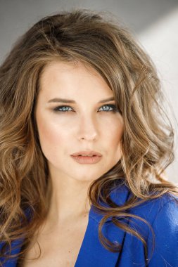 Portre stüdyo portre güzel kıvırcık kadın giyiyor mavi ceket, gri duvar arka plan