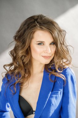 Portre stüdyo portre güzel kıvırcık kadın giyiyor mavi ceket, gri duvar arka plan