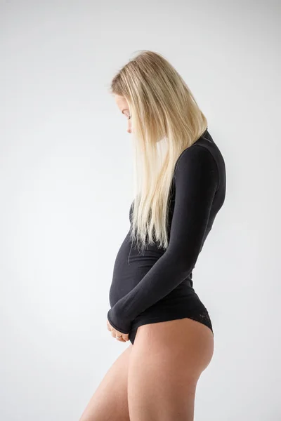 スタジオポートレートの妊娠中のブロンド女性で黒服に立って白い壁の背景 — ストック写真