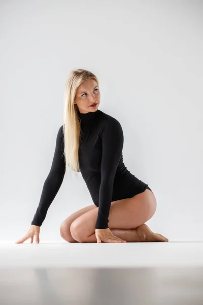 Studio Porträtt Sportig Blond Kvinna Svarta Kläder Sitter Golvet Vit — Stockfoto