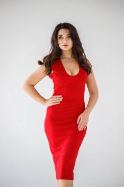 Gri duvar arkasında poz veren kırmızı elbiseli güzel esmer kadının şık stüdyo portresi.  