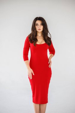 Gri duvar arkasında poz veren kırmızı elbiseli güzel esmer kadının şık stüdyo portresi.  