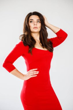 Gri duvar arkasında poz veren kırmızı elbiseli güzel esmer kadının şık stüdyo portresi.  