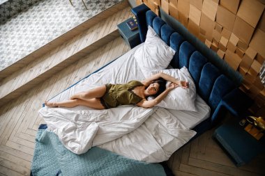 İç çamaşırlı, yatakta poz veren güzel esmer manken.