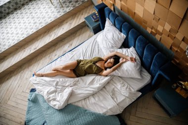 İç çamaşırlı, yatakta poz veren güzel esmer manken.