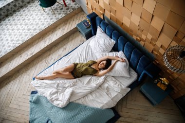 İç çamaşırlı, yatakta poz veren güzel esmer manken.