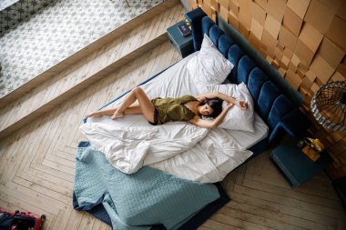 İç çamaşırlı, yatakta poz veren güzel esmer manken.